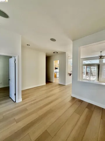 Wood-finish flooring throughout, recessed ceiling lighting, and a white interior door