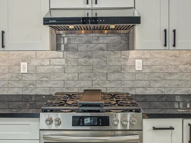 Stove has Griddle Pan and modern hood vent.