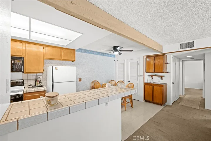 Kitchen with tile counters, original 1983 cabinetry, pantry storage