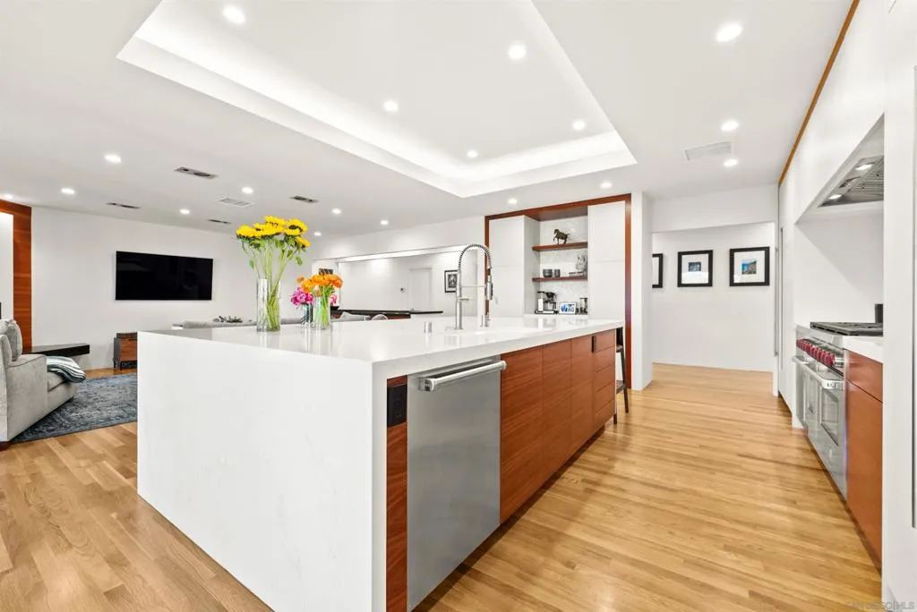 Modern kitchen bathed in natural light with quartz countertops, center island, hardwood floors and a Wolf 8-burner range, wine cooler