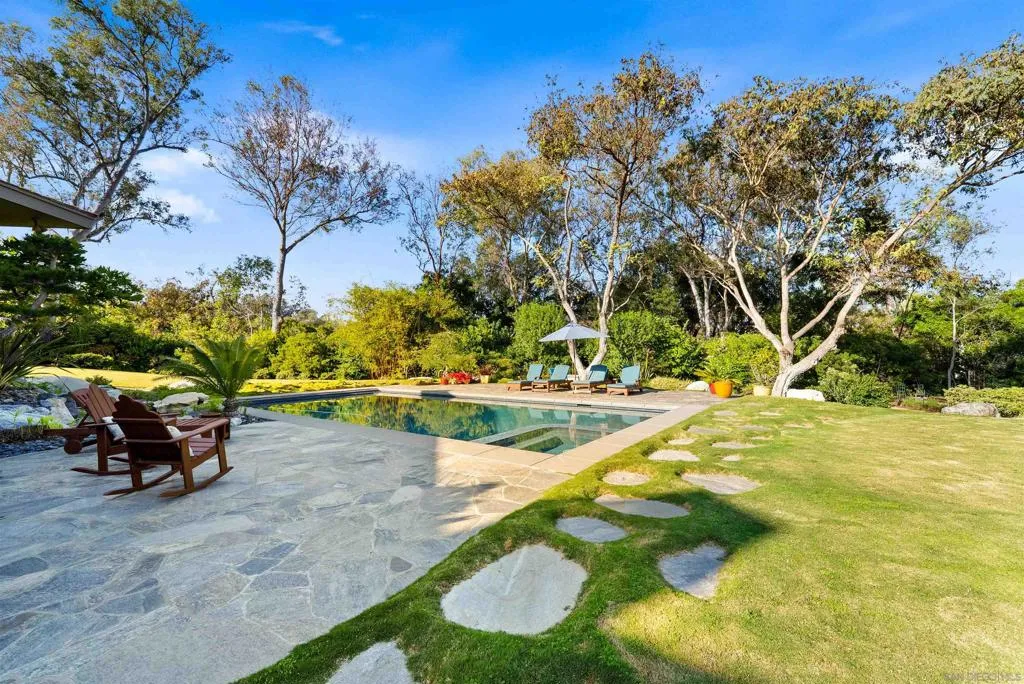 The backyard includes large grassy areas, covered patios with outdoor dining, and an outdoor fire pit perfect for enjoying the night sky