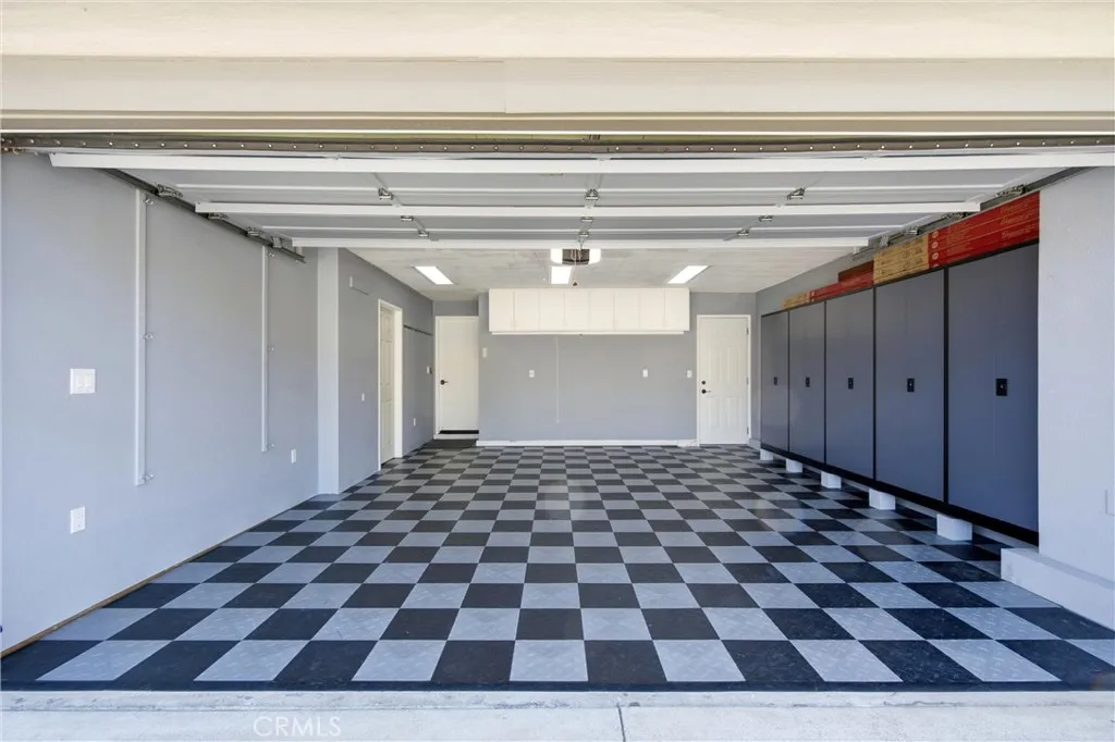 Expansive garage with built-in cabinetry, additional attic storage, and checkerboard flooring.