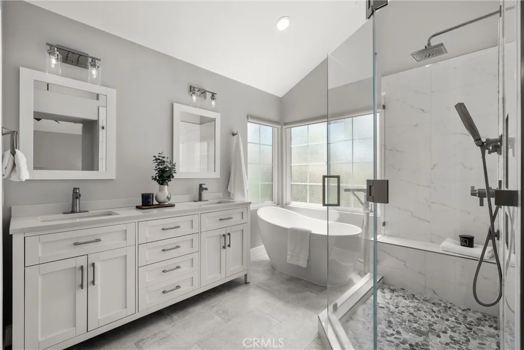 Beautifully updated primary bathroom featuring a dual-sink vanity, freestanding soaking tub, and spacious walk-in shower.