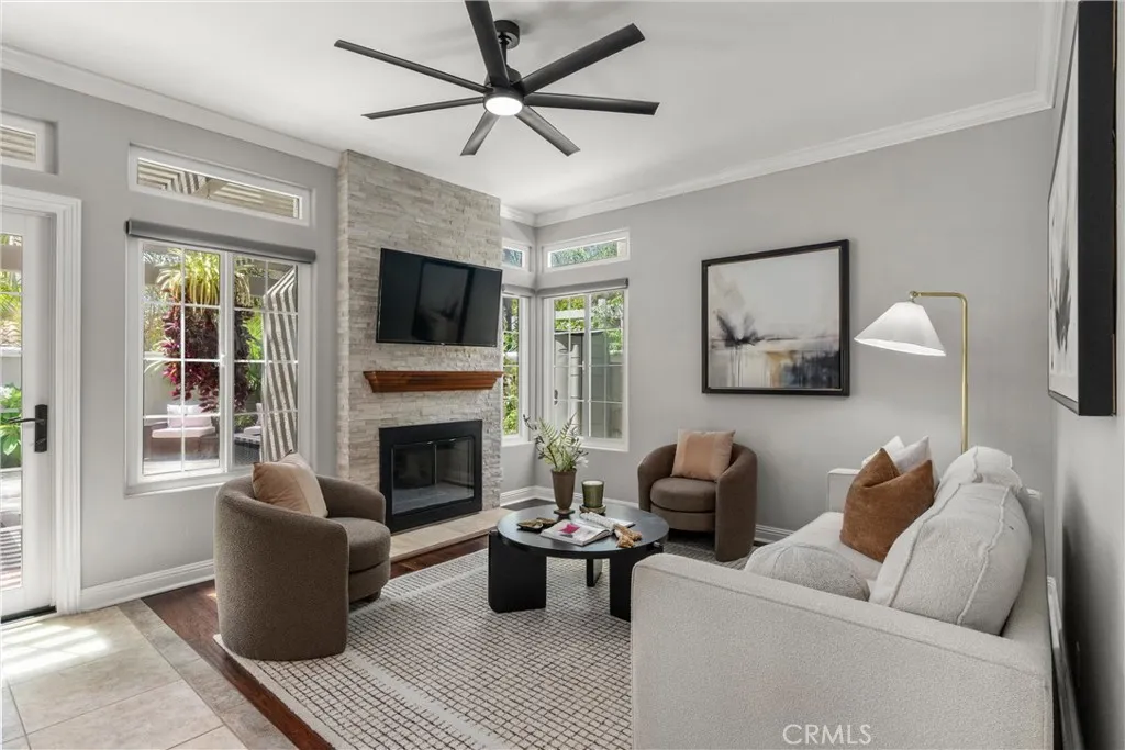 Inviting family room with stone fireplace, ceiling fan, plantation shutters and hardwood flooring.