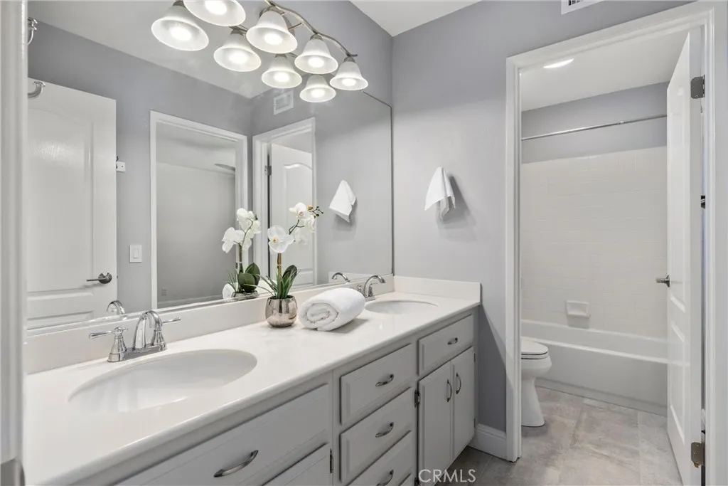 Bright secondary bathroom with dual-sink vanity, generous counter space, and a separate tub/shower area.