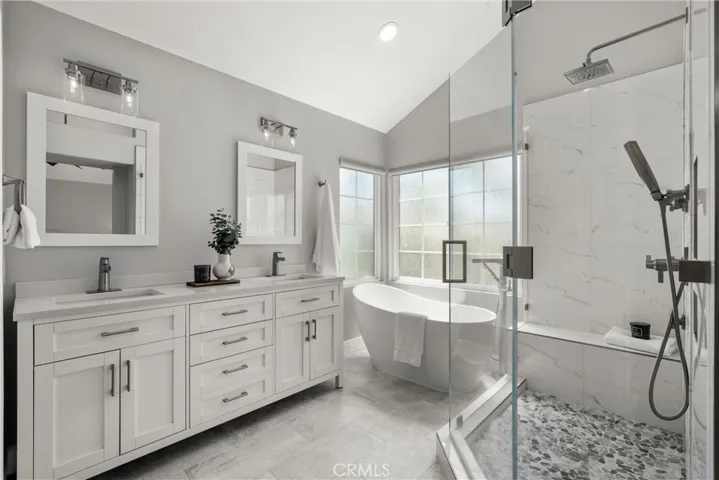 Beautifully updated primary bathroom featuring a dual-sink vanity, freestanding soaking tub, and spacious walk-in shower.