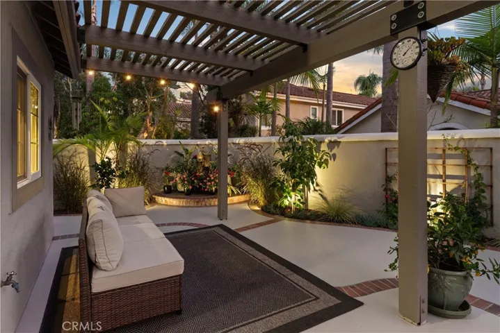 Outdoor living area with pergola-covered seating, fire feature, and lush landscaping.