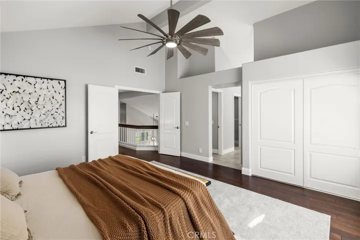 Spacious primary bedroom featuring vaulted ceiling, hardwood flooring and generous closet space.