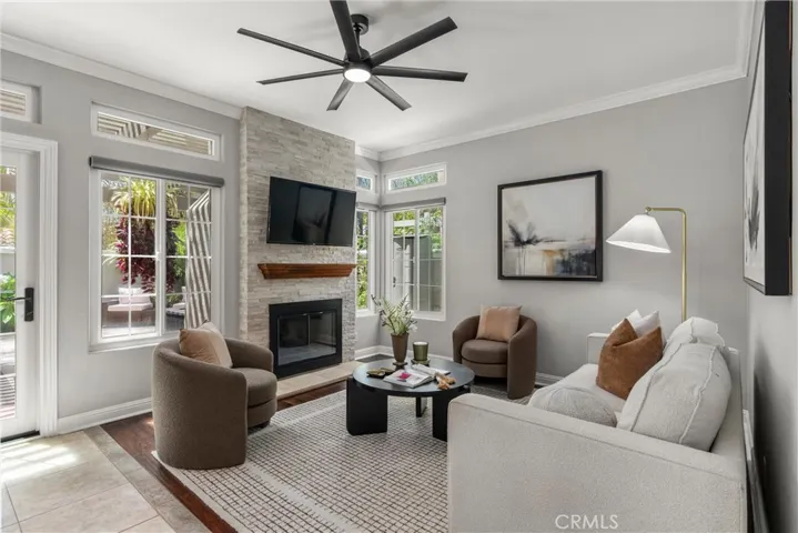 Inviting family room with stone fireplace, ceiling fan, plantation shutters and hardwood flooring.