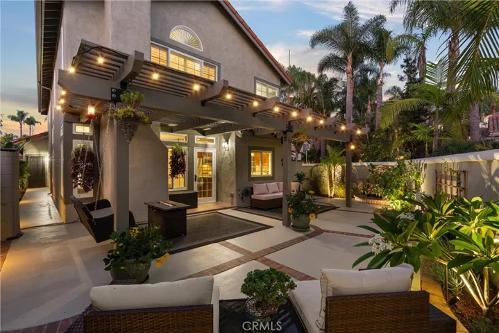 Outdoor living area with pergola-covered seating, fire feature, and lush landscaping.