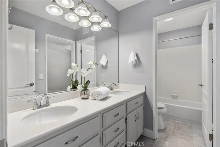 Bright secondary bathroom with dual-sink vanity, generous counter space, and a separate tub/shower area.