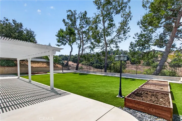 Spacious backyard featuring a covered patio and built-in planters perfect for a vegetable garden.