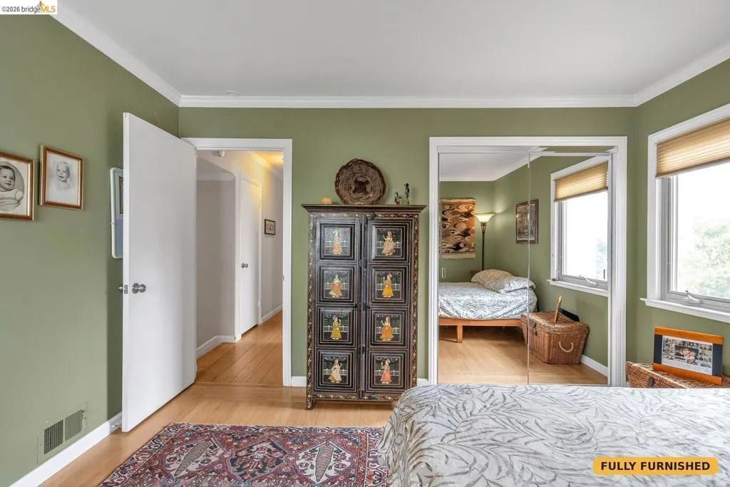 Bedroom 2 on northeasterly corner of the home with queen bed, corner desk and chair, mirrored sliding closet doors and antique dresser/cabinet.