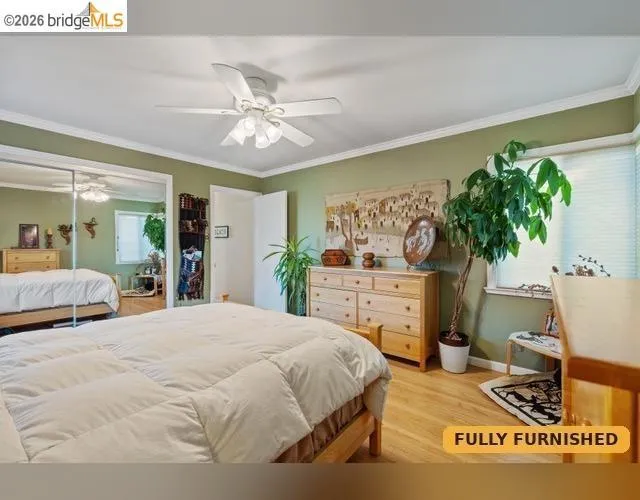Wood-finish flooring, crown molding, ceiling fan, mirrored closet doors, and recessed lighting