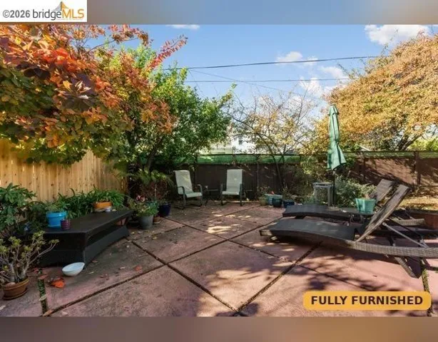 Paved patio with sun loungers, gas BBQ, and perimeter fencing