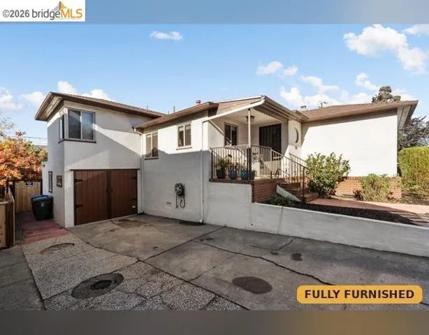 Split-level exterior with stucco finish, a covered entry, parking for two (tandem). Garage door is faux, space was converted to finished laundry and extra space.