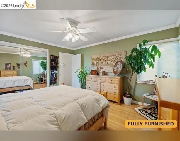 Wood-finish flooring, crown molding, ceiling fan, mirrored closet doors, and recessed lighting
