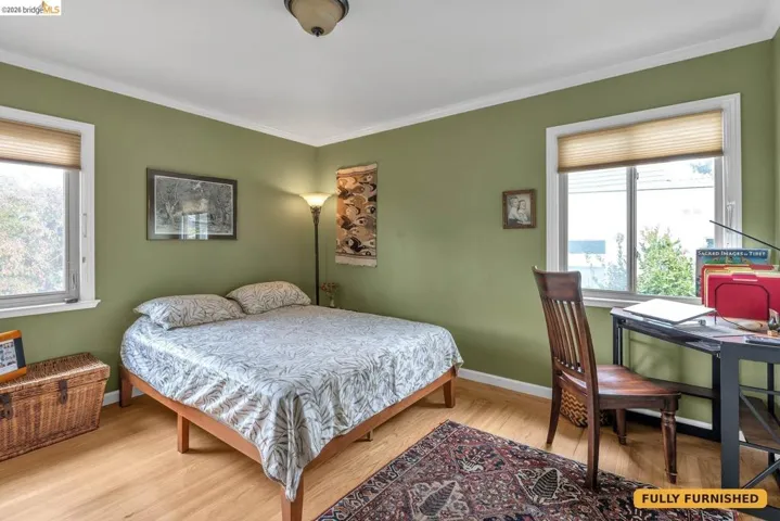 Bedroom 2 on northeasterly corner of the home with queen bed, corner desk and chair, mirrored sliding closet doors and antique dresser/cabinet.