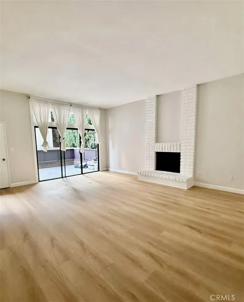 Living room with high ceiling, fireplace and sliding doors open to the front patio Living room with high ceiling, fireplace and sliding doors open to the front patio