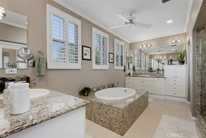 Primary en-suite with separate soaking tub, dual vanities, and dual walk-in closets