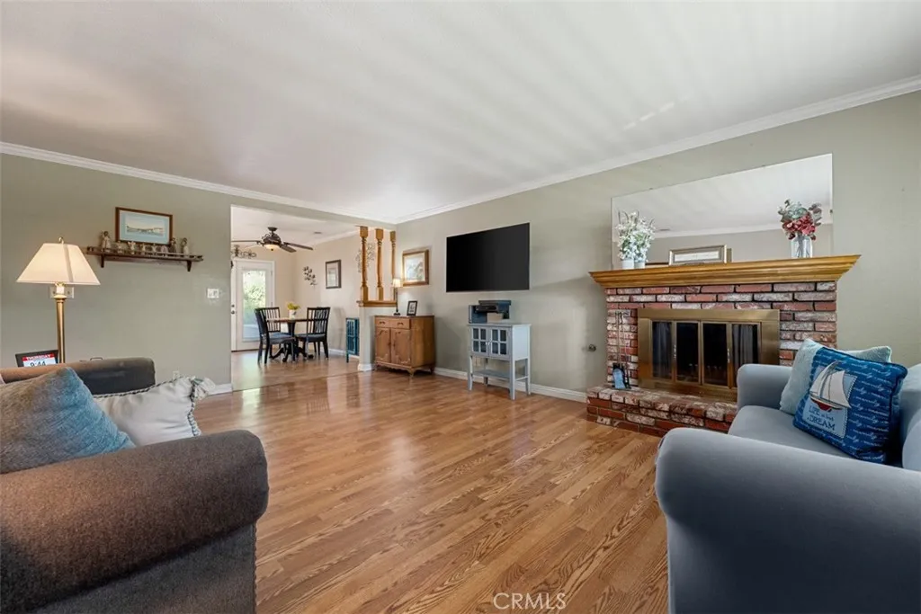 Living room area upon entry complete with hardwood floors, fireplace, crown molding , plantation shutters and Dual pane windows Living room area upon entry complete with hardwood floors, fireplace, crown molding , plantation shutters and Dual pane windows