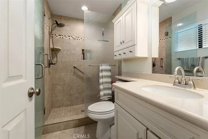 Custom tile enclosure at shower with stone countertops at vanity and tile flooring