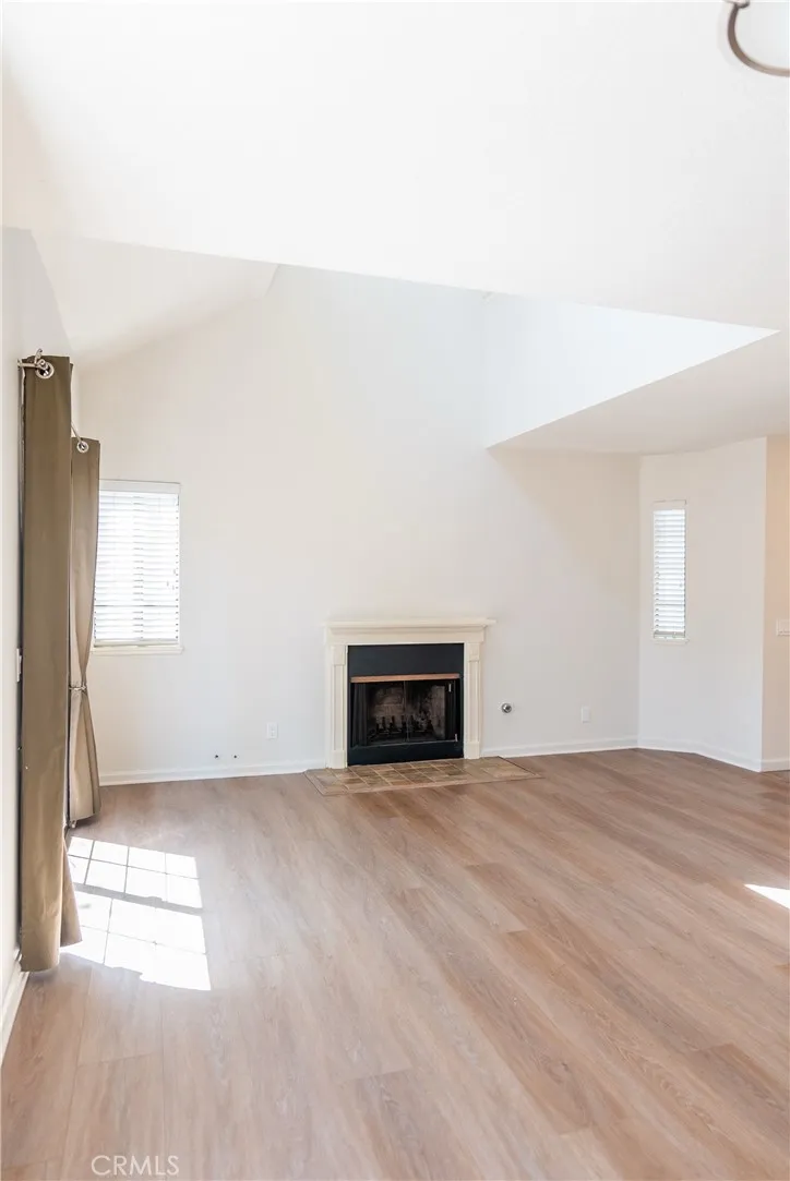 Open and airy living room featuring vaulted ceilings, fireplace, and abundant natural light.