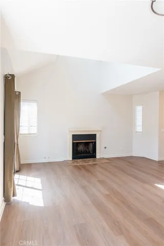 Open and airy living room featuring vaulted ceilings, fireplace, and abundant natural light.
