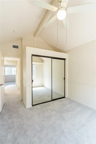Spacious bedroom with vaulted ceiling, natural light, and fresh carpet.