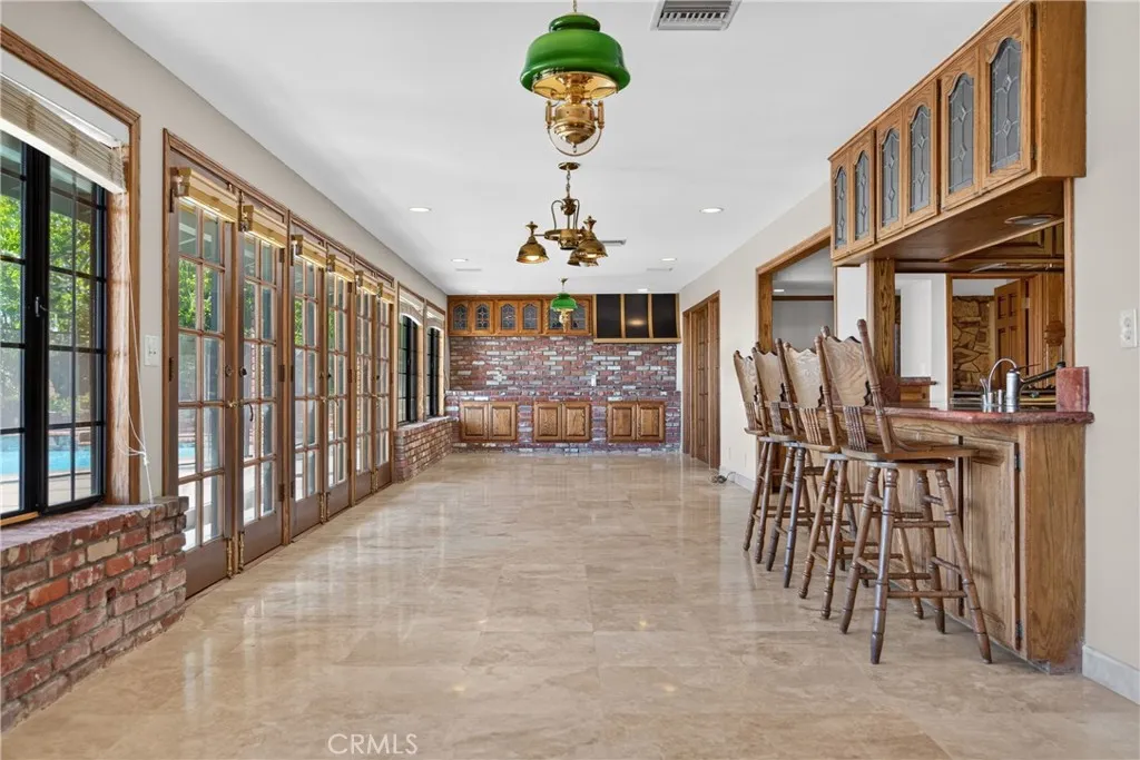 Entertaining room with wall of windows/ glass doors adjacent to kitchen, with butler pantry, 2nd fireplace and access and views to backyard
