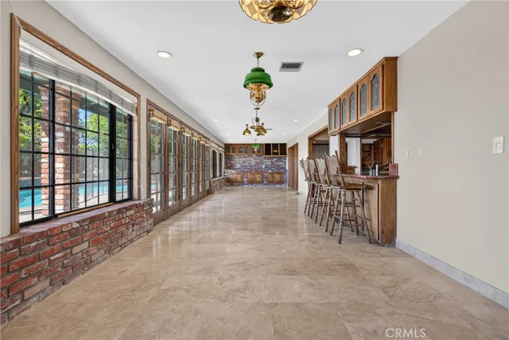 Entertaining room with wall of windows/ glass doors adjacent to kitchen, with butler pantry, 2nd fireplace and access and views to backyard