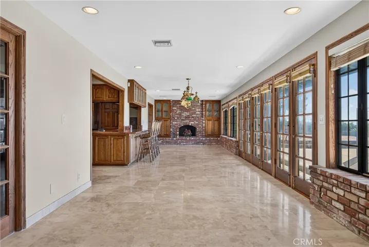 Entertaining room with wall of windows/ glass doors adjacent to kitchen, with butler pantry, 2nd fireplace and access and views to backyard