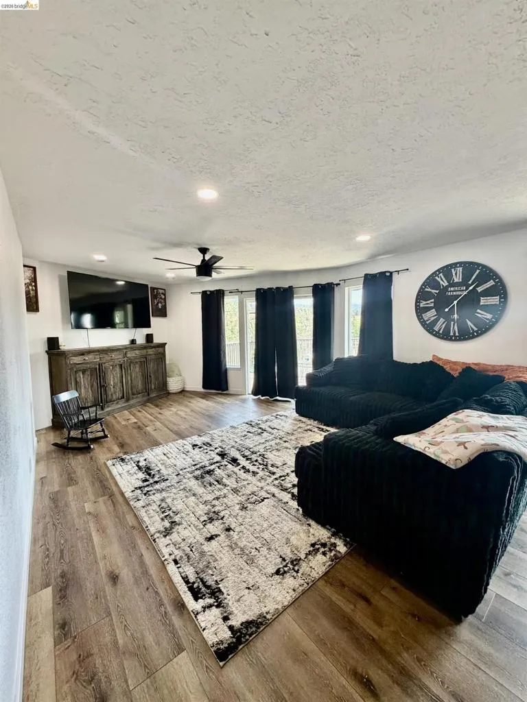 Recessed lighting, wood-finish flooring, ceiling fan, and multiple windows with dark-toned window coverings