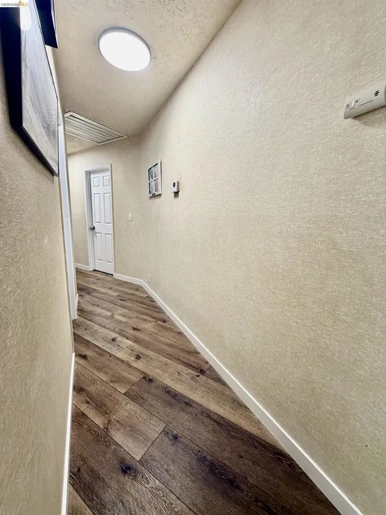 Wood-finish flooring, textured wall finish, overhead flush-mount lighting, and crisp white trim
