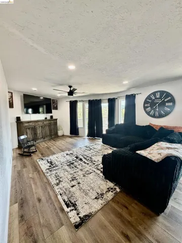 Recessed lighting, wood-finish flooring, ceiling fan, and multiple windows with dark-toned window coverings