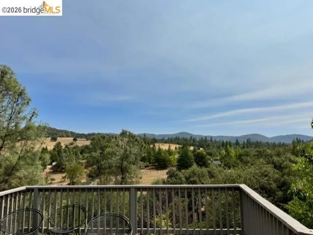 Expansive outdoor deck with wood railing, offering broad rural and mountainous scenery