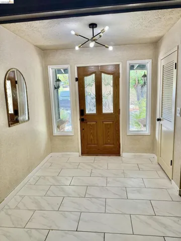 Entryway featuring a decorative front door with etched glass, white framed windows, and a modern sputnik chandelier