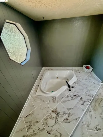 Built-in soaking tub with a white finish, surrounded by large format tile in a geometric pattern