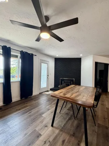 Wood-finish flooring, modern ceiling fan with integrated lighting, recessed ceiling lighting, and a painted brick fireplace surround