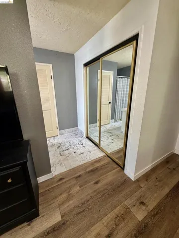Wood-finish flooring, gold-framed mirrored closet doors, and marble-look tile flooring