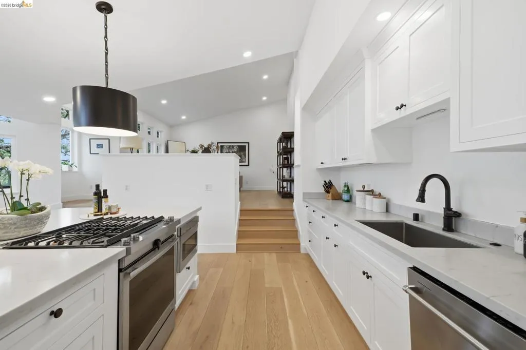 Spacious kitchen featuring white cabinetry, light countertops, wood-finish flooring, and a stainless steel gas range with a matching oven Spacious kitchen featuring white cabinetry, light countertops, wood-finish flooring, and a stainless steel gas range with a matching oven