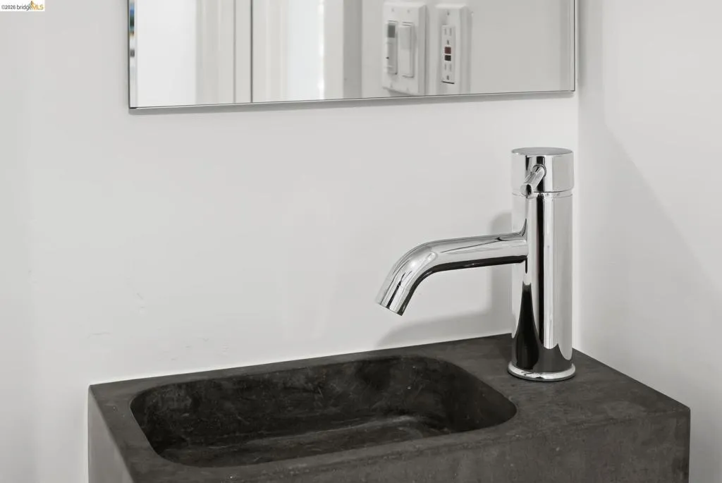Wall-mounted rectangular mirror, chrome single-handle faucet, and dark vessel sink Wall-mounted rectangular mirror, chrome single-handle faucet, and dark vessel sink
