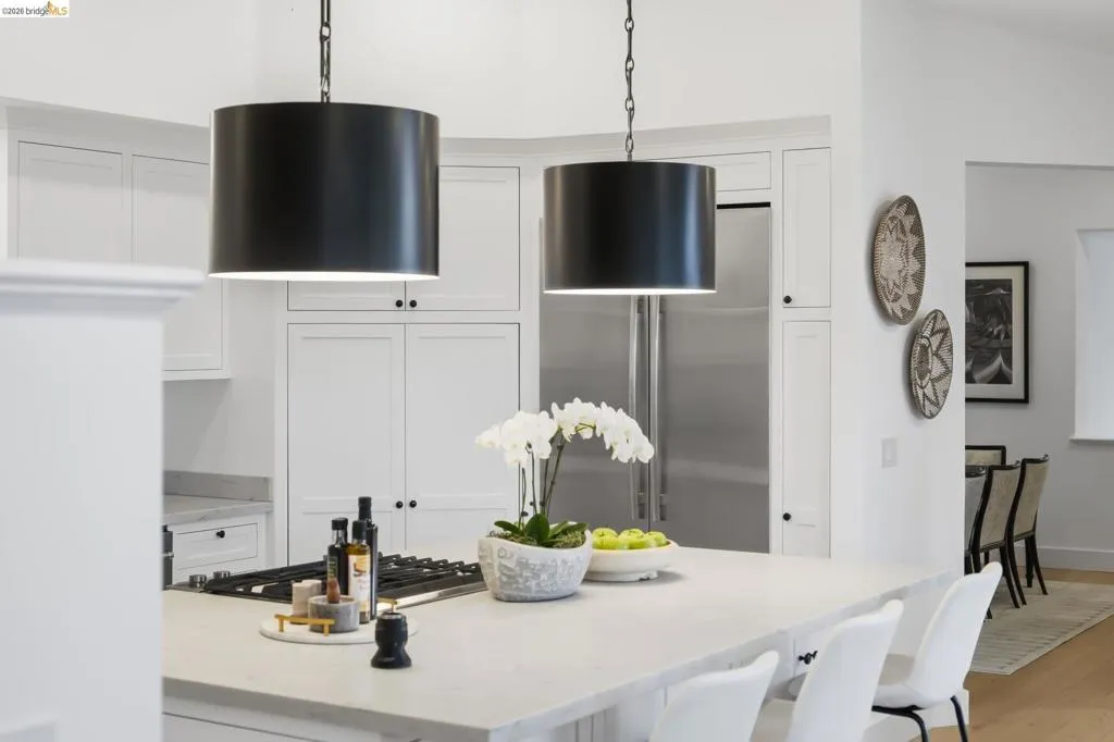 Kitchen island with integrated cooktop, stone countertop, and two pendant light fixtures Kitchen island with integrated cooktop, stone countertop, and two pendant light fixtures
