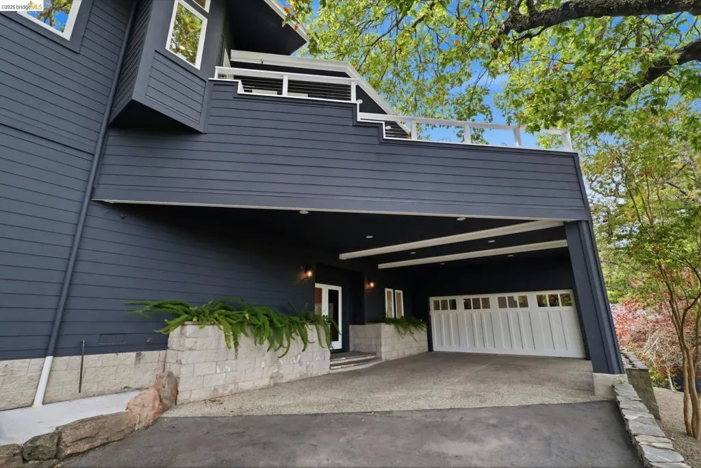 Modern exterior with dark siding, a covered carport, and a white paneled garage door Modern exterior with dark siding, a covered carport, and a white paneled garage door