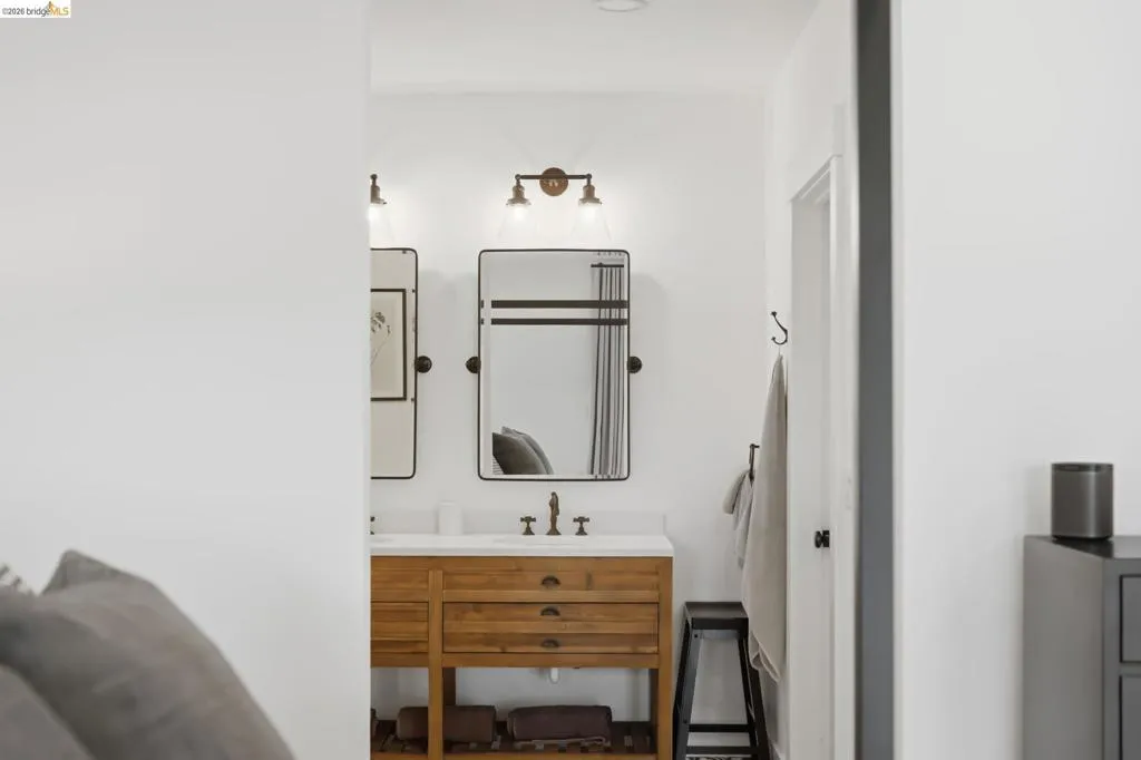 Wood-finish vanity with white countertop, dual framed mirrors, and sconce lighting Wood-finish vanity with white countertop, dual framed mirrors, and sconce lighting