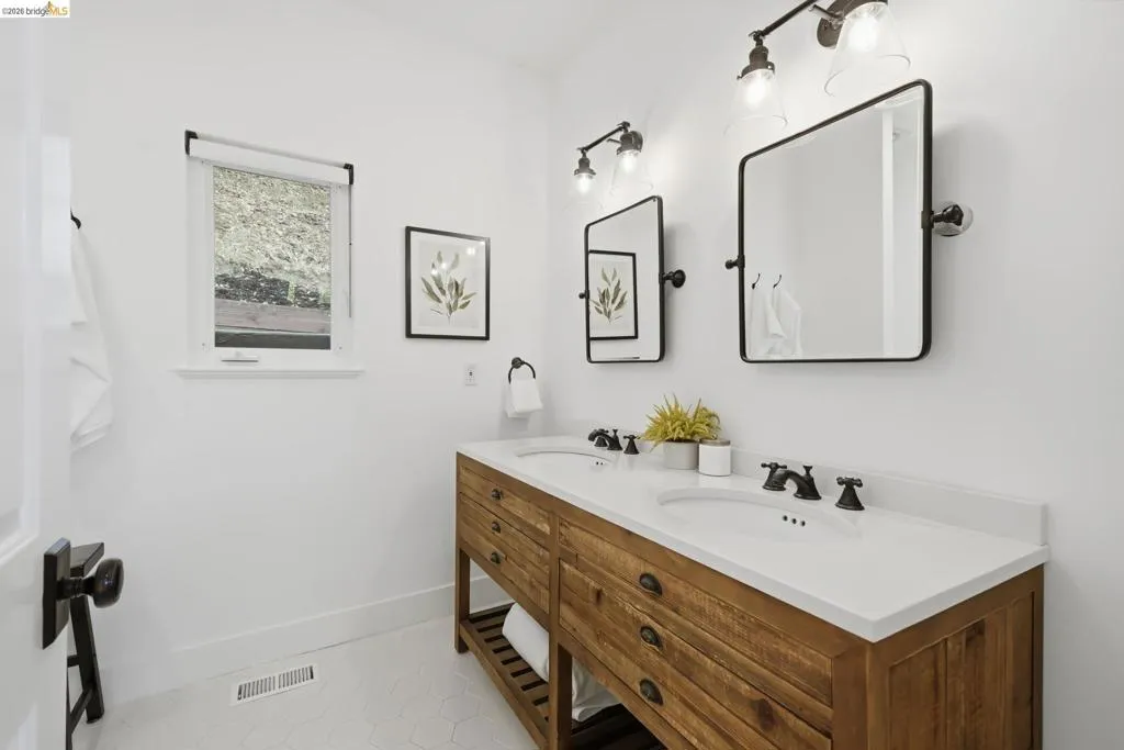 Double vanity with wood-finish cabinetry, integrated dual sinks, and white countertops Double vanity with wood-finish cabinetry, integrated dual sinks, and white countertops