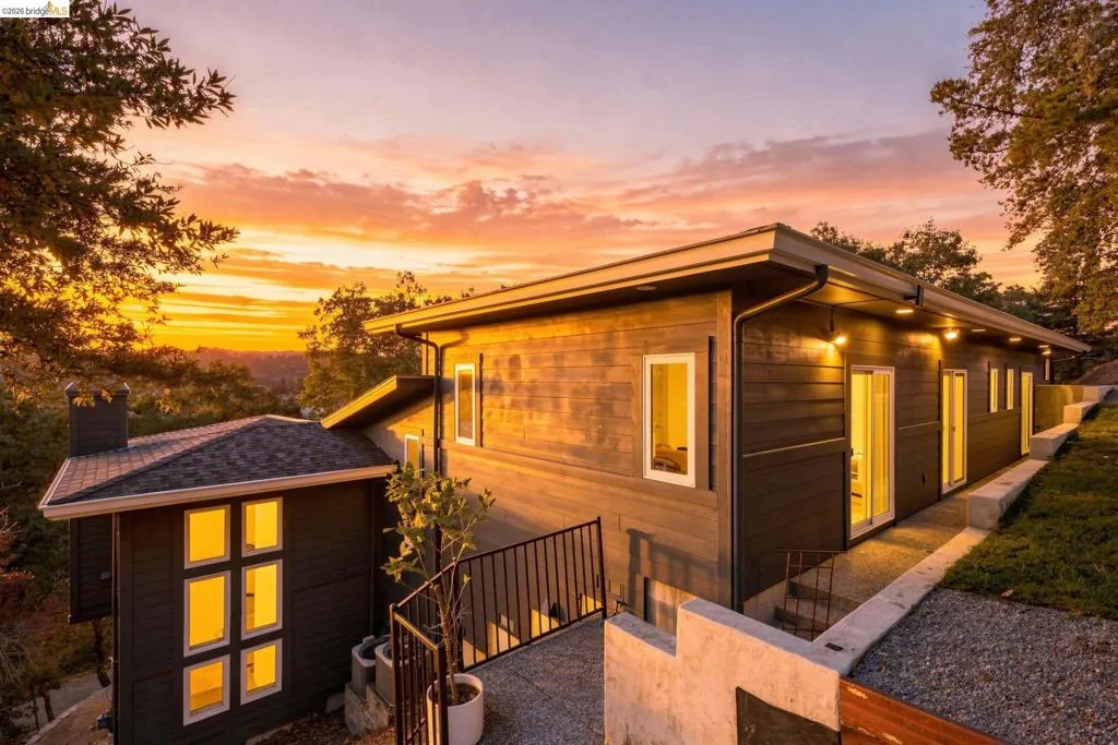 Multi-level exterior with horizontal siding, multiple sliding glass doors, white-framed windows, and integrated exterior lighting Multi-level exterior with horizontal siding, multiple sliding glass doors, white-framed windows, and integrated exterior lighting