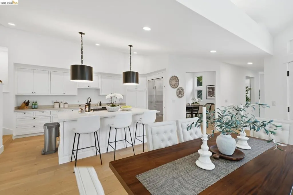 Open-concept space featuring wood-finish flooring, a kitchen island with seating, pendant lighting, and recessed lighting Open-concept space featuring wood-finish flooring, a kitchen island with seating, pendant lighting, and recessed lighting