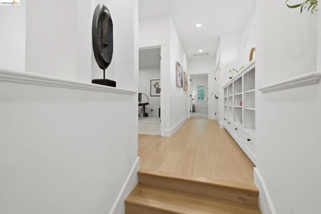 Hardwood flooring, recessed lighting, white built-in shelving, and white walls Hardwood flooring, recessed lighting, white built-in shelving, and white walls