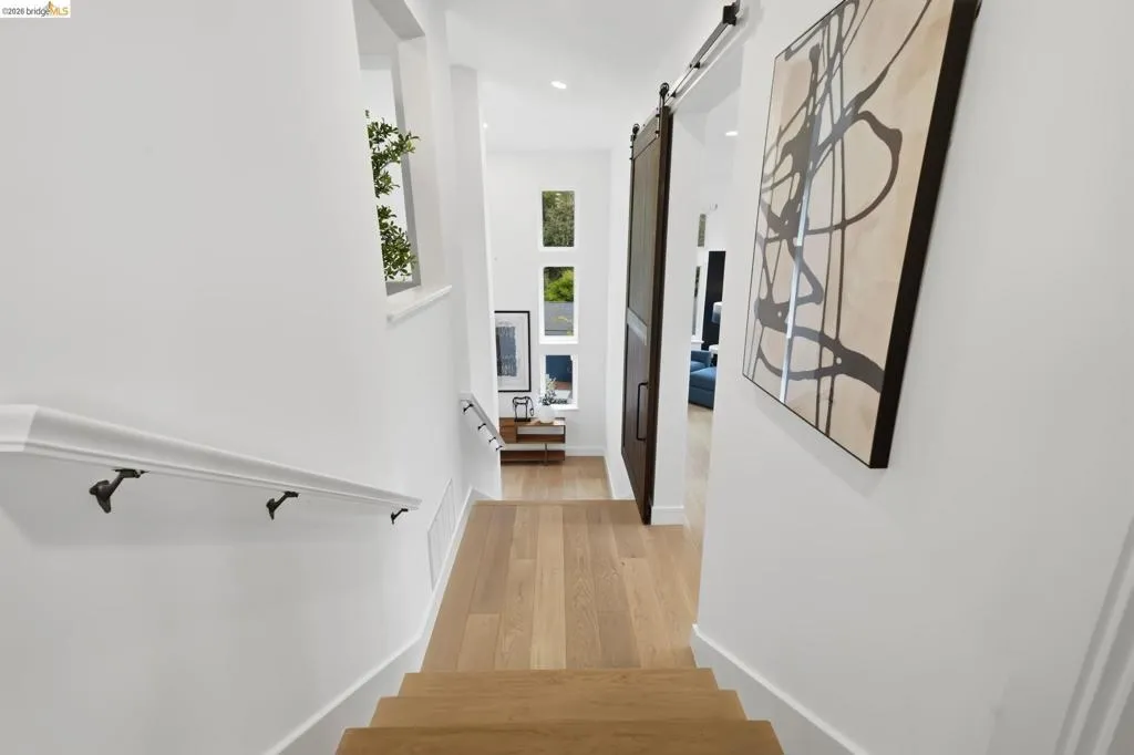 Hardwood flooring, multi-pane windows, white walls, black handrail brackets, and a sliding barn door Hardwood flooring, multi-pane windows, white walls, black handrail brackets, and a sliding barn door